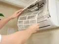 Osoba wyjmuje filtr z jednostki wewnętrznej klimatyzacji split, aby go wyczyścić.