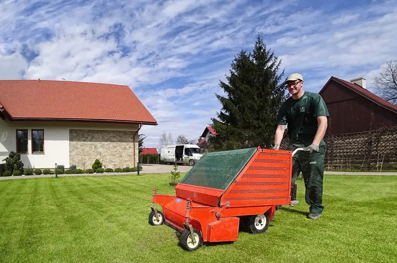 Ogrodnik z wózkiem do aeracji trawnika, który pomoże jak pozbyć się mchu z trawnika.